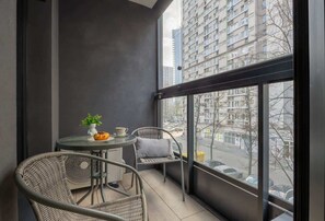 A balcony with a table and chairs, a potted plant, and a view of a cityscape. - Elegant Apartment with Balcony | Close to Metro, Place to Work (Warszawa)