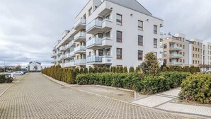 A multi-story residential building with balconies, a paved driveway, and a hedge-lined entrance. - Apartment with Garden | Place to Work | Close to the Lake (Gdansk)