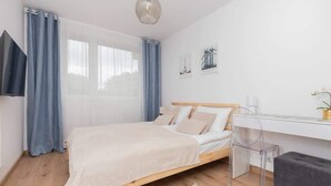 A modern bedroom with a wooden bed, a desk, and a chair. - Apartment with Garden | Place to Work | Close to the Lake (Gdansk)