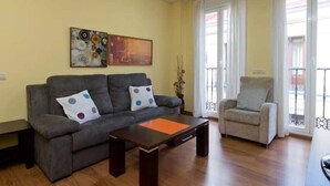 Un soggiorno con un divano grigio, un tavolino, una poltrona grigia e due quadri appesi al muro.