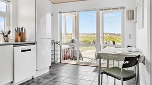 Una cocina con un ventanal grande, una mesa de comedor y una silla.