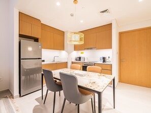 Eine moderne Küche mit Holzschränken, einem Edelstahlkühlschrank, einem Gasherd und einem Esstisch mit Stühlen.