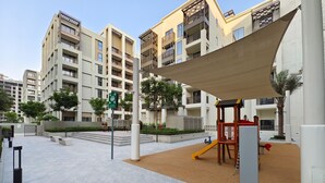 Un moderno complejo residencial con un parque infantil, zona de estar exterior y área cubierta.