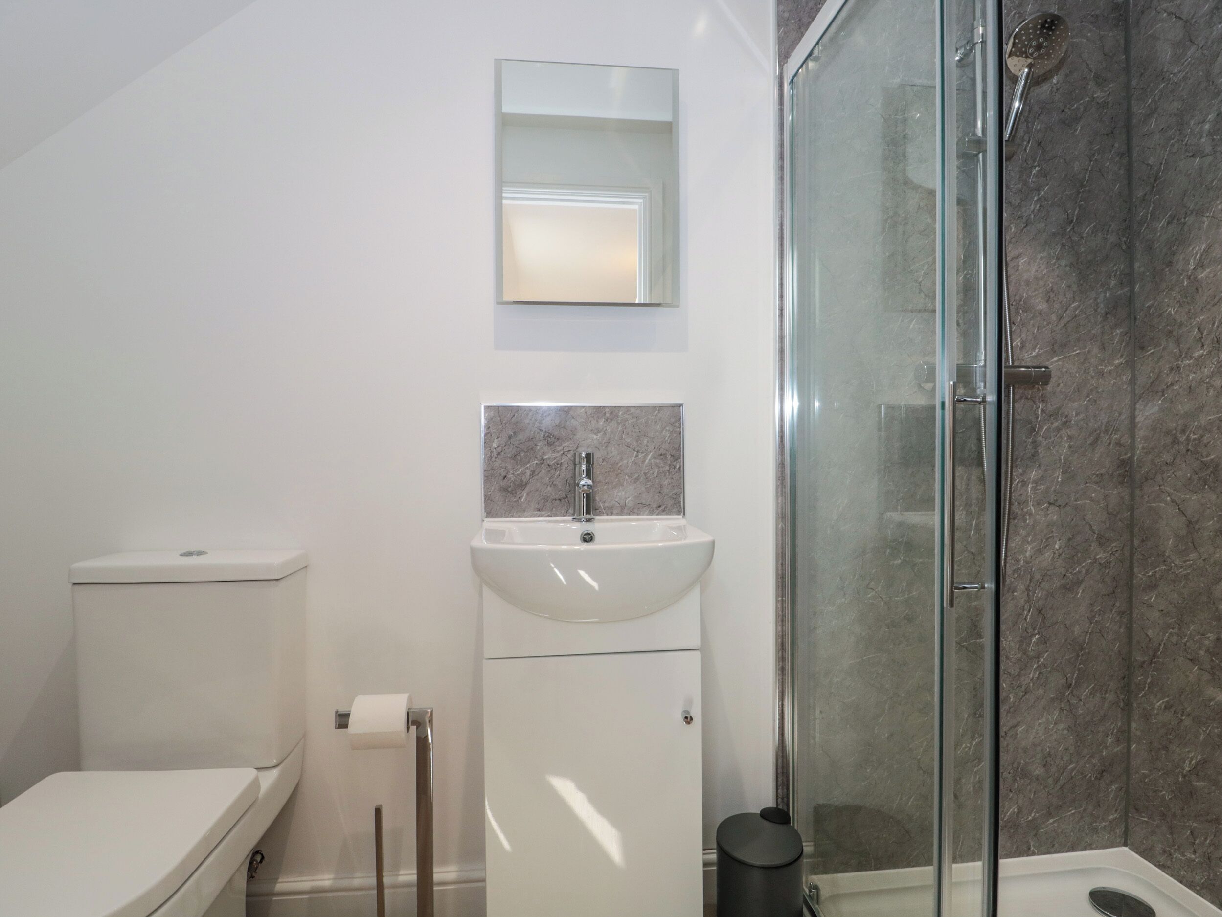 Ein modernes Badezimmer mit Toilette, Waschbecken und Duschkabine.