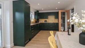 Una cocina moderna con armarios oscuros, encimera de madera y un comedor con mesa y sillas.