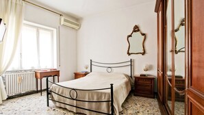 A bedroom with a metal bed frame, a wooden nightstand, a bedside table, a mirror, and a radiator. - Large & Quiet Home in Rome Monteverde (Roma)