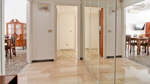 A spacious room with a large mirror, a dining area with wooden furniture, and a hallway leading to another room. - Large & Quiet Home in Rome Monteverde (Roma)