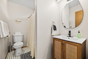 A bathroom with a toilet, sink, mirror, and shower curtain. - Two Adjacent Apartments for Large Groups (3539) (Boise)