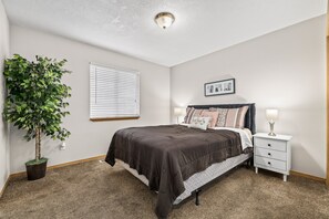 A bedroom with a bed, bedside table, lamp, and a potted plant. - Two Adjacent Apartments for Large Groups (3539) (Boise)