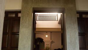 Een deur die leidt naar een kamer met een lage plafond, een grote potplant en een beeld.