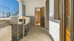A modern kitchen with a dining area, a view of the outside, and a bathroom visible through an open door. - 3777 Appartamento Space Family by Barbarhouse (Manduria)
