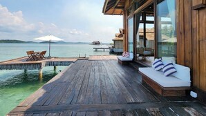 A wooden deck with a wooden bench and a table, overlooking a body of water. - Full Moon Private Island (Kiri Sakor)
