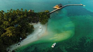 An aerial view of a tropical island with a beach, a wooden pier, and a small house. - Full Moon Private Island (Kiri Sakor)