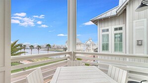 A balcony with a table and chairs, overlooking a body of water and buildings. - Pet-Friendly, Pool-Side Beach Home@Cinnamon Shore W/20+ Resort-Like Amenities (Port Aransas)