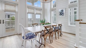 A dining area with a white table and chairs, large windows, and a hanging light fixture. - Pet-Friendly, Pool-Side Beach Home@Cinnamon Shore W/20+ Resort-Like Amenities (Port Aransas)