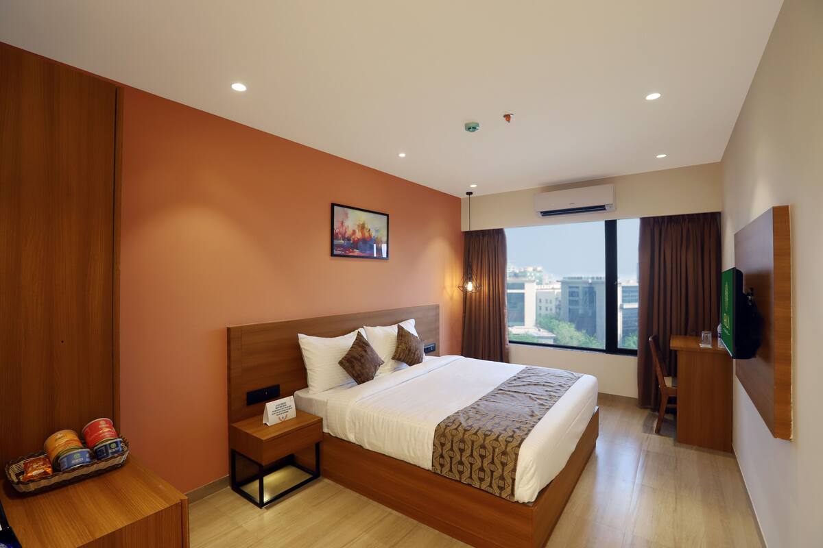 Une chambre d’hôtel avec un grand lit, un bureau, une télévision et une fenêtre donnant sur la ville.