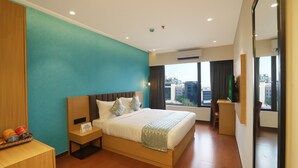 A hotel room with a large bed, a desk, and a view of the city. - Aralia - A Business Hotel MIDC (Mumbai)