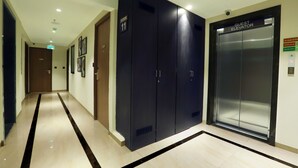 A hotel corridor with a guest elevator, a door labeled "Floor 11", and a sign indicating the use of stairs in case of fire. - Aralia - A Business Hotel MIDC (Mumbai)