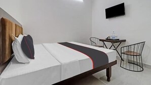 Een hotelkamer met een bed, een bureau, een stoel, een flatscreen televisie en een wandlamp.