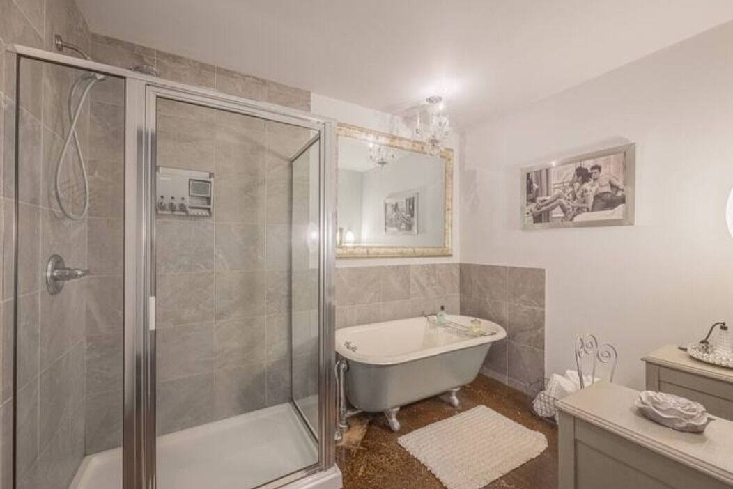Un baño con ducha envuelta en vidrio, una bañera independiente y un tocador con espejo.