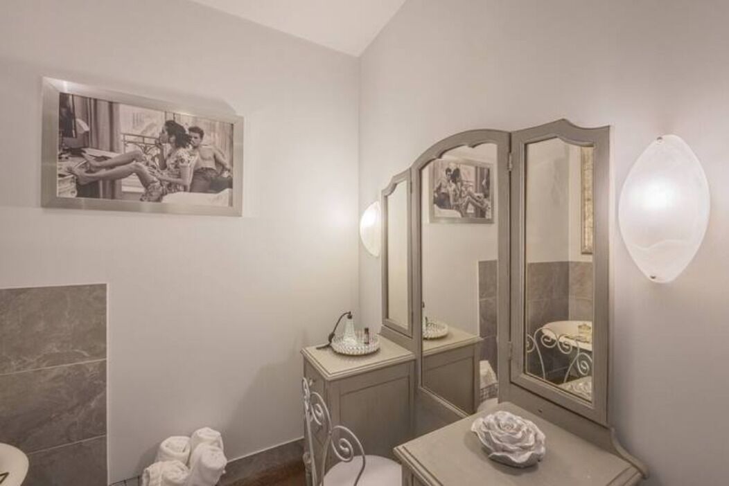 Un bany amb un lavabo, un mirall gran i una fotografia emmarcada a la paret.