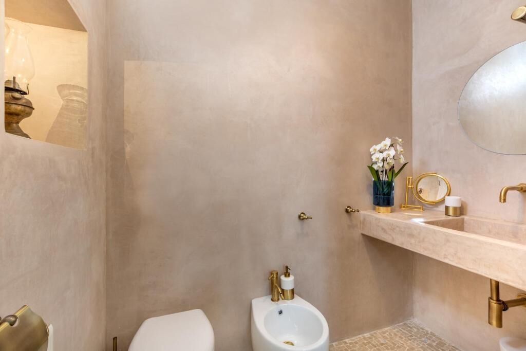 A bathroom with a toilet, bidet, and sink with gold fixtures.