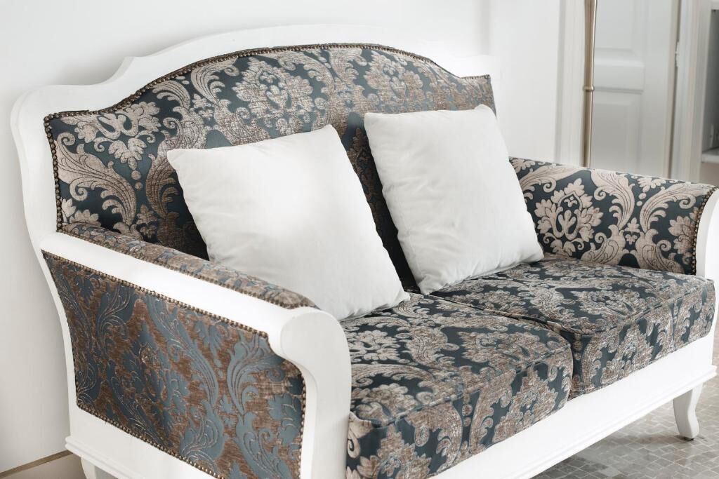 A white sofa with a patterned fabric and two white cushions.