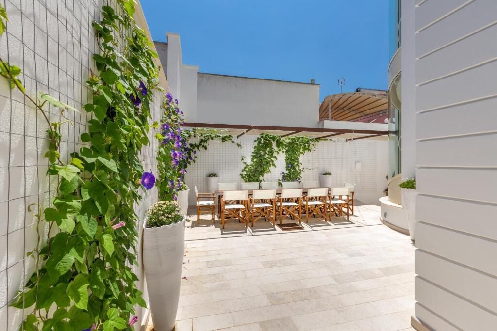A patio with a table and chairs, surrounded by white walls and a tiled floor.