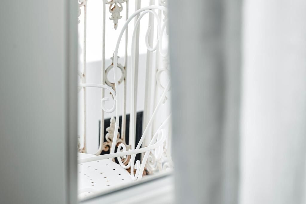 A white metal gate with intricate designs, likely leading to a room or area within a building.