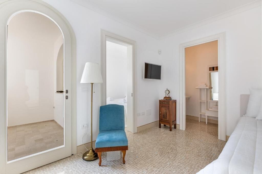 A bedroom with a bed, a chair, a lamp, a TV, and a wardrobe.