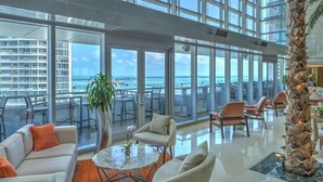 A spacious indoor area with large windows offering ocean views, modern furniture, and a decorative plant. - Miami Luxury Executive Apartment (Miami)