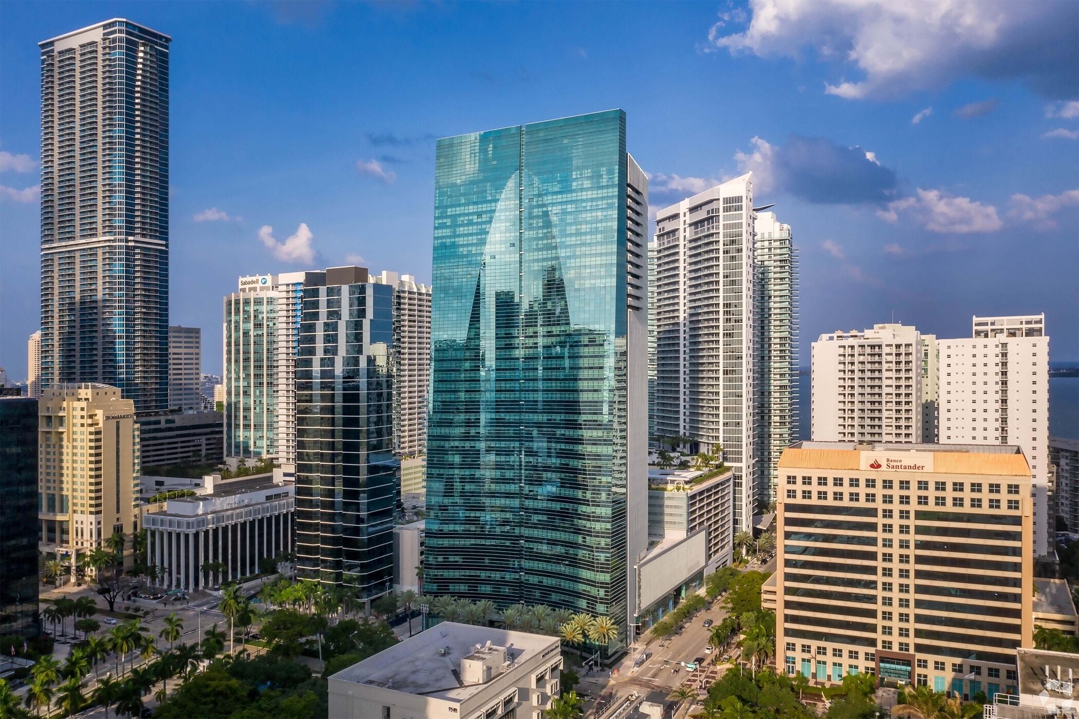 A cityscape with modern high-rise buildings, including a prominent glass skyscraper reflecting the city skyline.