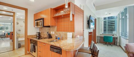 A modern kitchen with wooden cabinets, a granite countertop, and stainless steel appliances.