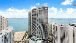 A high-rise hotel with multiple floors, a rooftop pool, and a view of the sea and a bridge. - Miami Luxury Executive Apartment (Miami)