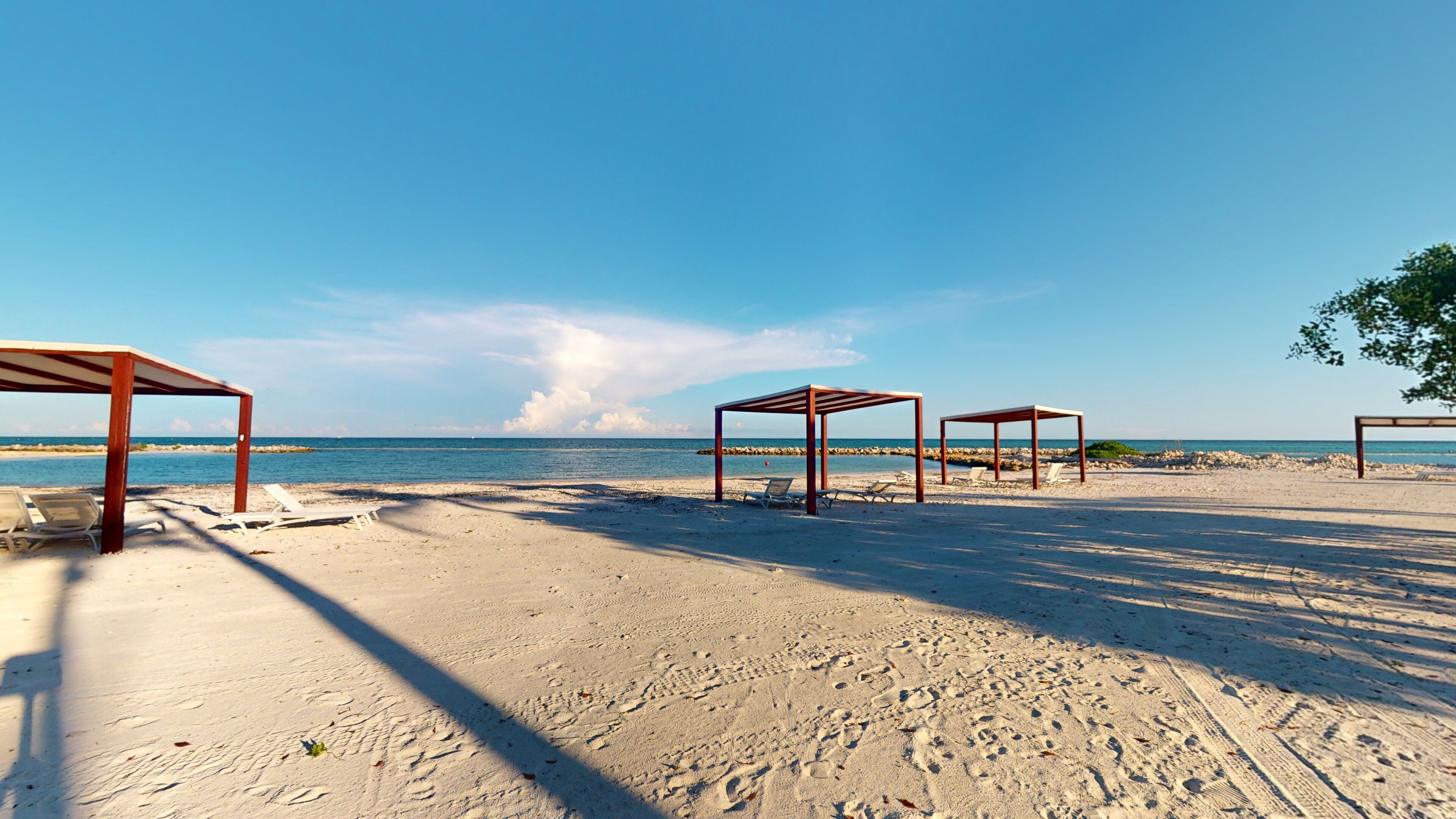 Une plage avec des structures en bois et des chaises longues.