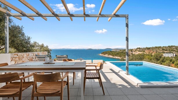 Zona relax all'aperto con piscina e vista sul mare.