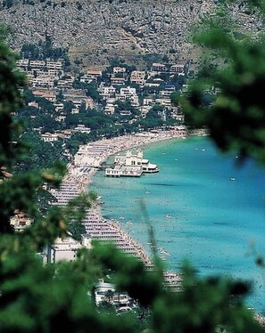 A coastal town with buildings along the waterfront, a marina with boats, and a prominent building with a dome.