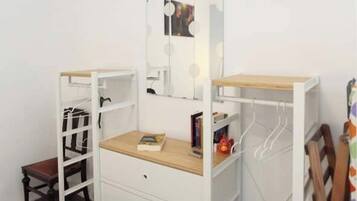 Une pièce blanche avec un lit, un bureau et une armoire.