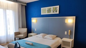 Una habitación de hotel con cama, una silla, un escritorio y teléfono.