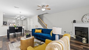 A modern living room with a blue sofa, yellow armchair, and a fireplace. - Cheerful Abode (Raleigh)