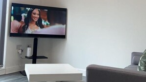 Un salon moderne avec un téléviseur à écran plat, un canapé aux lignes épurées, une table basse et une horloge murale.