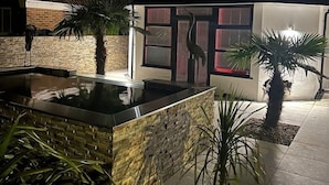 A modern house with a swimming pool, a balcony, and a well-lit entrance.
