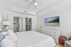 A bedroom with a bed, a dresser, a closet, and a television on the wall.
