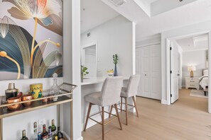 A modern interior with a dining area, bar, and a hallway leading to a bedroom.