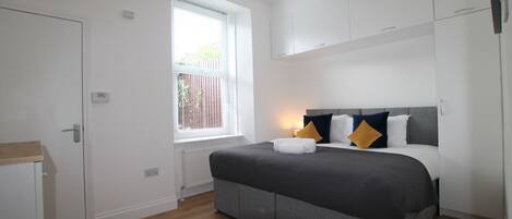 Un dormitorio con cama, ventana, radiador y armario.