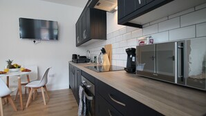 Een moderne keuken met donkere kastjes, een houten aanrecht, een ingebouwde magnetron en een koffiezetapparaat.