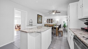 A modern kitchen with white cabinetry, granite countertops, and a dining area with wooden chairs and a table. - Pet-Friendly Tulsa Vacation Rental w/ Sunroom (Tulsa)