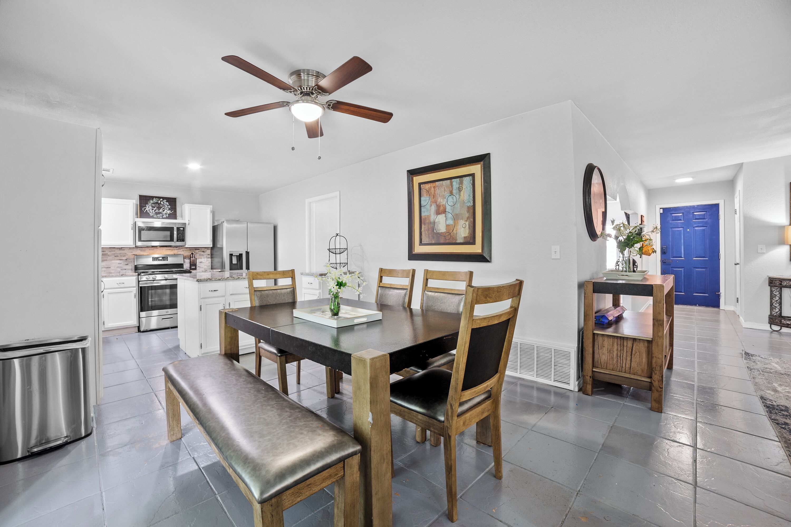 A modern kitchen with white cabinets, stainless steel appliances, and a dining area with a wooden table and chairs.