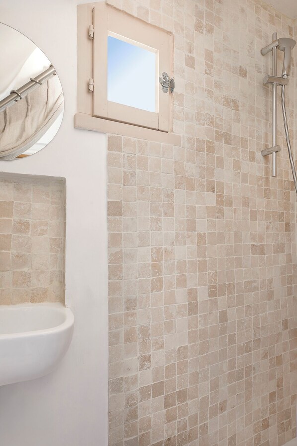 Un bagno con lavandino, specchio e doccia.