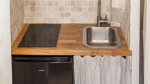 A compact kitchenette with a black dishwasher, a stainless steel sink, and a wooden countertop. - Le Mini - Un Voyage en Provence (Aix-en-Provence)